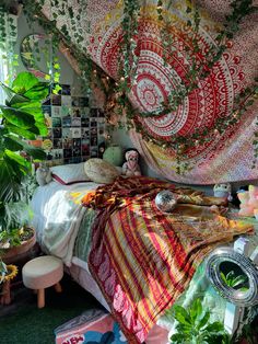 a bedroom with lots of hanging plants and blankets on the bed, along with various potted plants