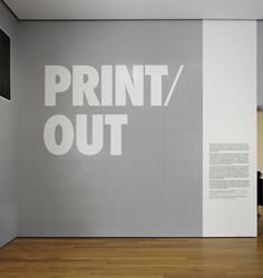 a large white wall with the words print out on it in front of a wooden floor