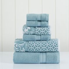 a stack of blue towels sitting on top of a white table next to a wall