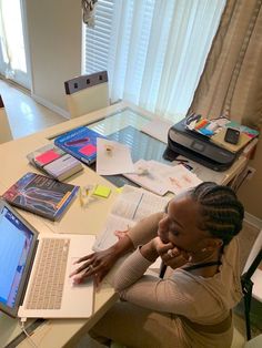 a woman sitting at a desk with a laptop and papers on the table next to her