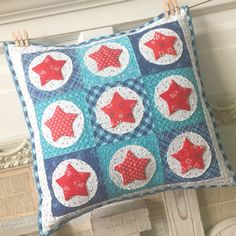 a blue and red quilted pillow with stars on it hanging from a clothesline