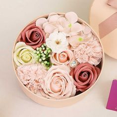 a pink box filled with lots of flowers next to a card and some other items