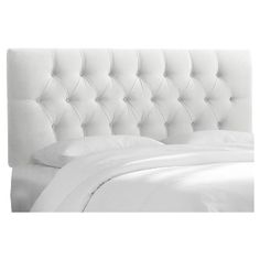 the headboard of a bed with white sheets and pillows