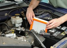 a man is working on an engine in his car with the hood up and it's air filter removed