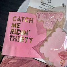 there is a pink paper bag on top of a plate that says catch me ridin'thirty