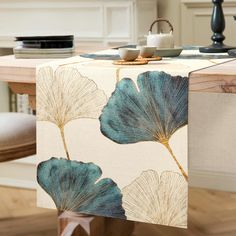 a table runner with blue leaves on it in front of a dining room table and chairs