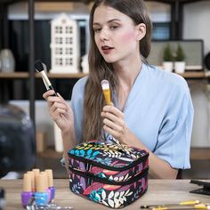 a woman sitting at a desk holding a brush and makeup bag