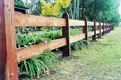 a wooden fence with plants growing on it and some trees in the backround