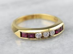 This is an interesting piece! Rather than the traditional alternating diamonds and rubies, this ring is set in a more intricate pattern with three diamonds at the center in a row of glowing red rubies. The quality of all of the stones is lovely, and the pattern lends itself well to being worn again against a variety of engagement rings... or stacked with other bands set with different gems for a glittering array of color. Metal: 18K Yellow Gold Gem: 3 Diamonds totaling .15 Carats, H in Color, VV Wedding Band Yellow Gold, Right Hand Ring, Stacking Bands, Family Jewellery, Right Hand Rings, Hand Ring, Star Ruby, Channel Set, Anniversary Bands