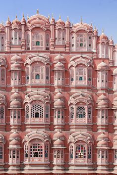 a large pink building with many windows and balconies on the top floor, in india