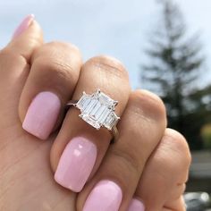 a woman's hand holding a pink manicure with a diamond ring on it