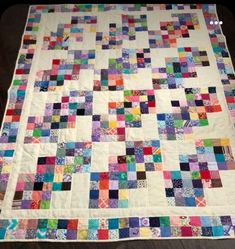 a multicolored quilt is displayed on a table