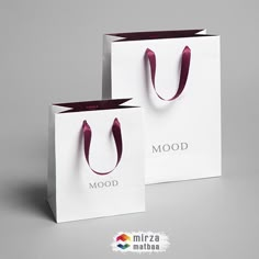 two white shopping bags with maroon handles are on the grey background, one is for mood