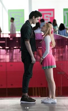 a man standing next to a woman in a pink dress