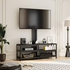 a flat screen tv sitting on top of a black entertainment center next to a potted plant