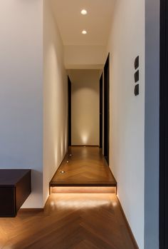 an empty hallway with wooden flooring and lighting