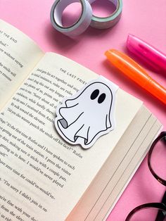 a book with a ghost sticker on it next to some pens and eye glasses