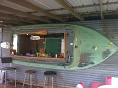 a green surfboard mounted to the side of a metal wall next to bar stools