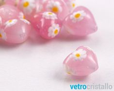 some pink and white glass beads with daisies on the top are laying next to each other