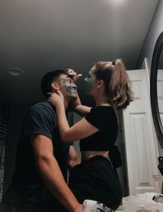 a man and woman standing in front of a mirror with their faces covered by masks