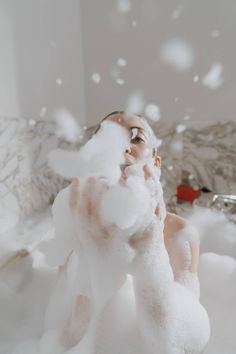 a woman is in the bathtub with foam on her face