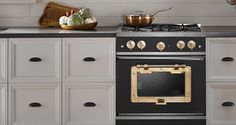 a black stove top oven sitting inside of a kitchen next to white cabinets and drawers