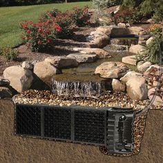 a garden pond with rocks and water flowing from the top to the bottom, surrounded by flowers