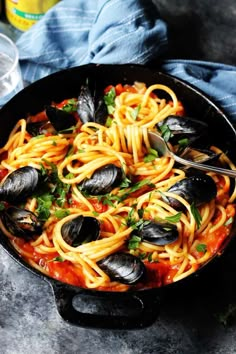 a skillet filled with spaghetti and mussels