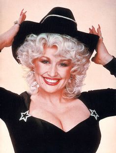 an older woman with blonde hair wearing a black hat and star earrings on her head