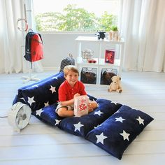 a young boy sitting on top of a blue pillow