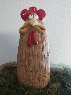 a wooden statue of a chicken with red eyes and a large beak on it's head