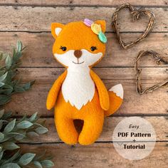 an orange stuffed fox sitting on top of a wooden table next to a heart shaped plant