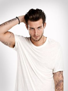 a young man with tattoos on his arms and shoulder, wearing a white t - shirt