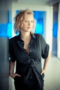 a woman standing in an office hallway with her hands on her hips and looking at the camera