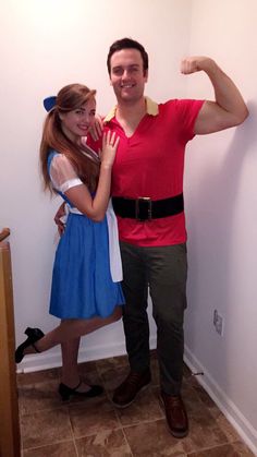 a man and woman posing for a photo in front of a wall with the arms up