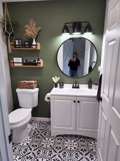 a woman taking a selfie in the mirror of a bathroom with black and white floor tiles