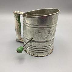 an old fashioned metal bucket with a green bead on the handle and two handles