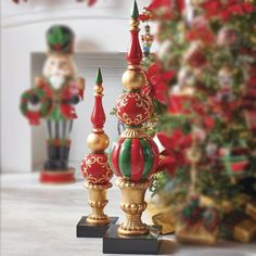 three christmas decorations are on display in front of a decorated tree and other holiday items