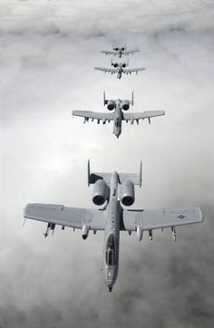 four airplanes flying in the sky above clouds