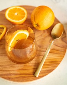 a wooden plate topped with orange slices and a glass filled with liquid