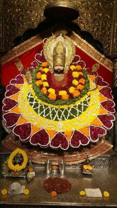 the statue is decorated with flowers and garlands on it's head, surrounded by other decorations