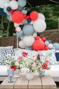 a table with vases and flowers on it in front of an outdoor party decoration