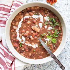 a white bowl filled with beans and sour cream on top of a red and white towel