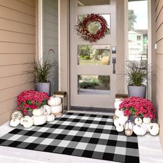 the front door is decorated with pumpkins and flowers