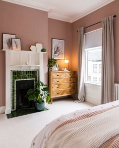 a bedroom with a fireplace, dresser and window