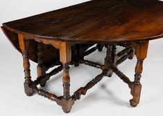 an old wooden table with turned legs on a white background in front of the camera