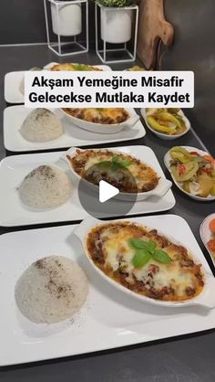 a table topped with white plates filled with different types of food on top of it