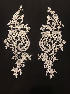 two white laces with flowers and leaves on a black background, one has an intricate design