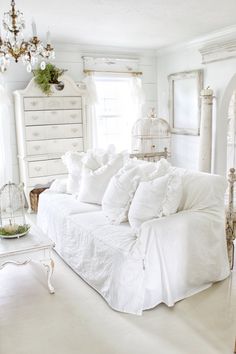 a white couch with lots of pillows on top of it in front of a window