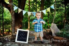 a young boy standing in front of a chalkboard sign